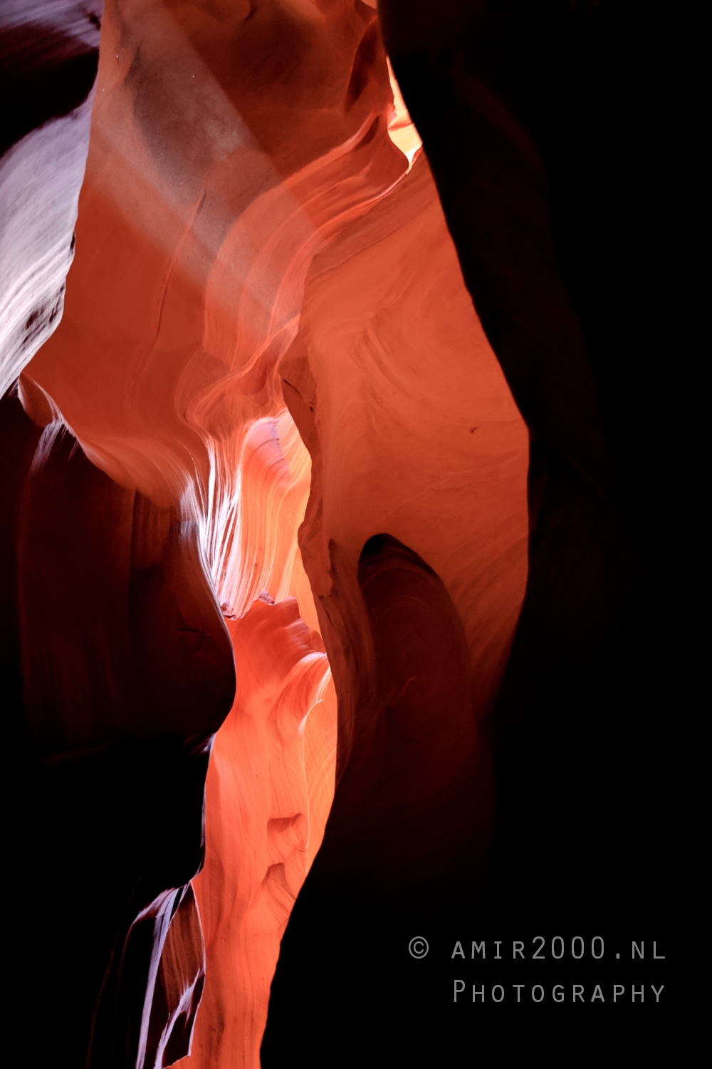 Sunbeam slicing through Antelope Canyon dust with warm sandstone walls in soft contrast