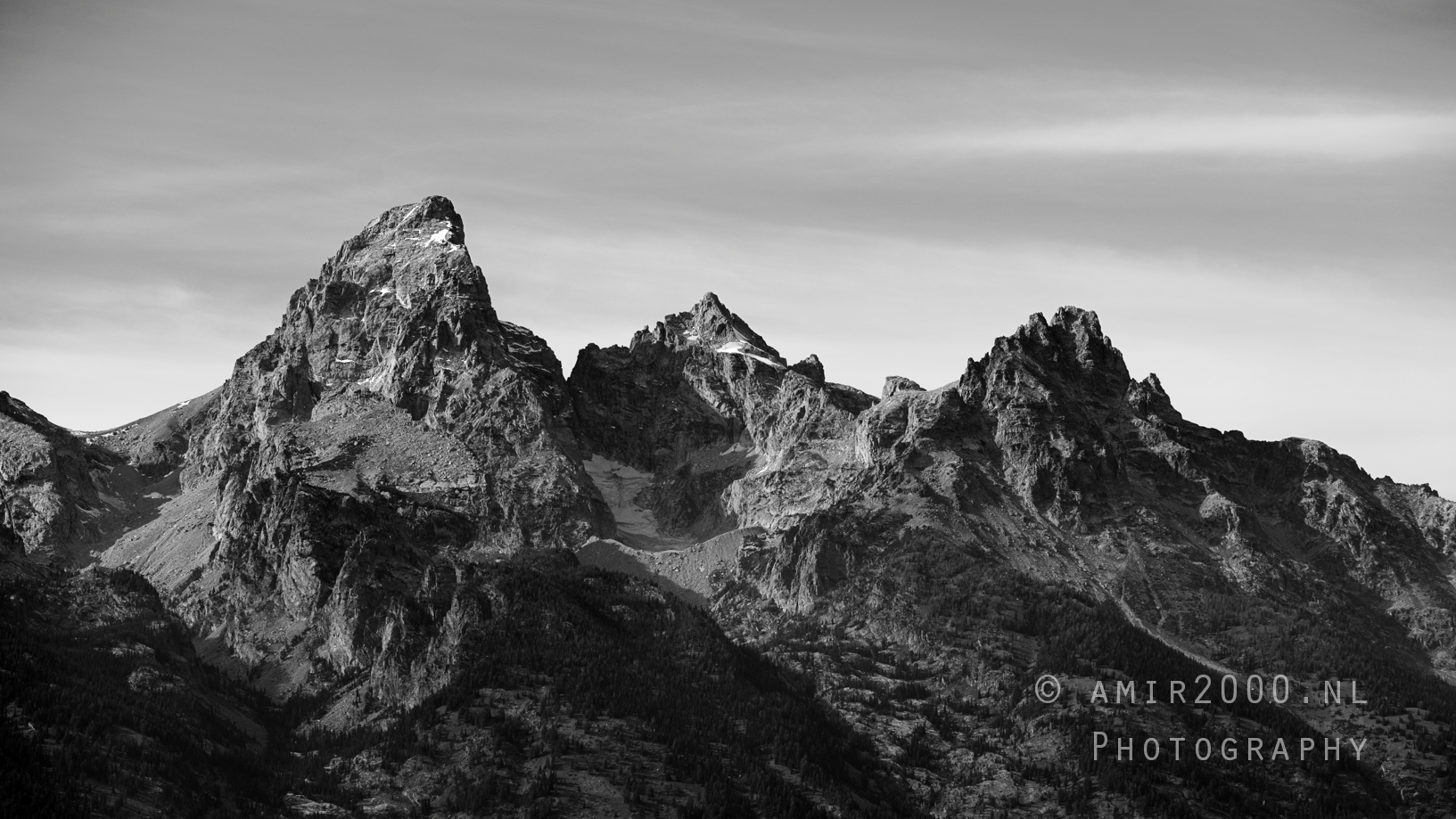 Black and white study of Grand Teton massif with ridgelines, glaciers, and high cloud band