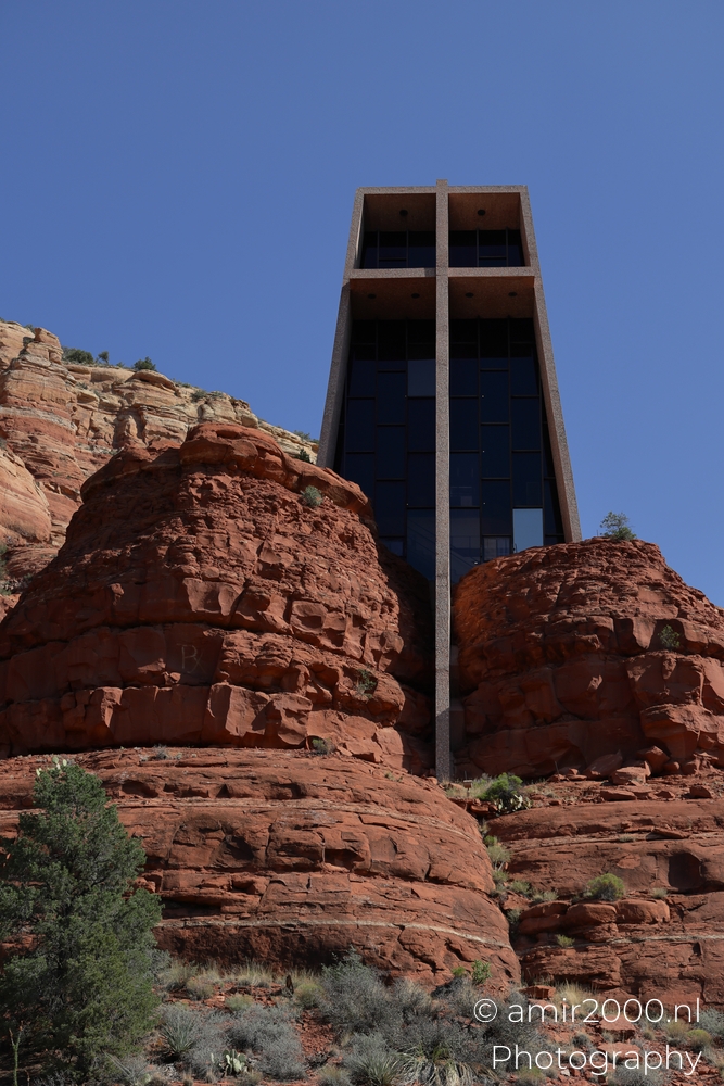 Front angle of the chapel above red rocks, deep blue sky and crisp shadow edges.