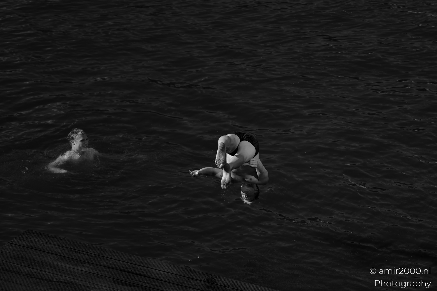 Tucked jump frozen mid air above an Amsterdam canal in monochrome