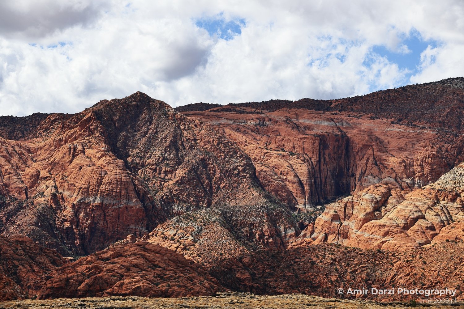 Stratified layers of reddish rocks with a cloudy sky above.
