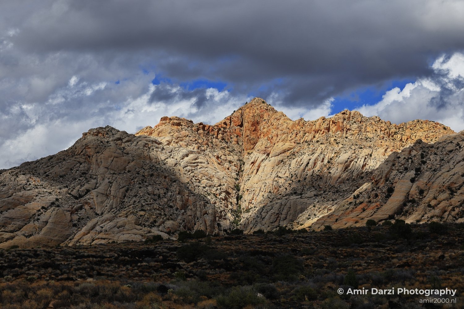 Rock-formation view of canyon landscape with sparse vegetation across desert ground in St George Utah.