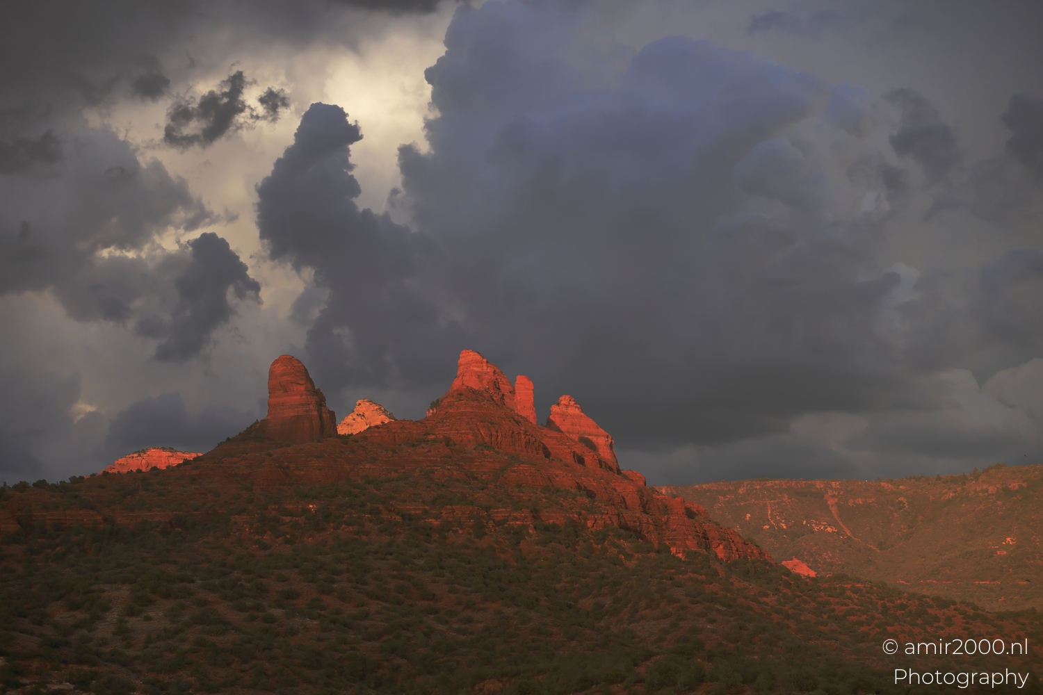 Sedona ridges from wide angle, pink sunset clouds, deep blue storm core over dark horizon.