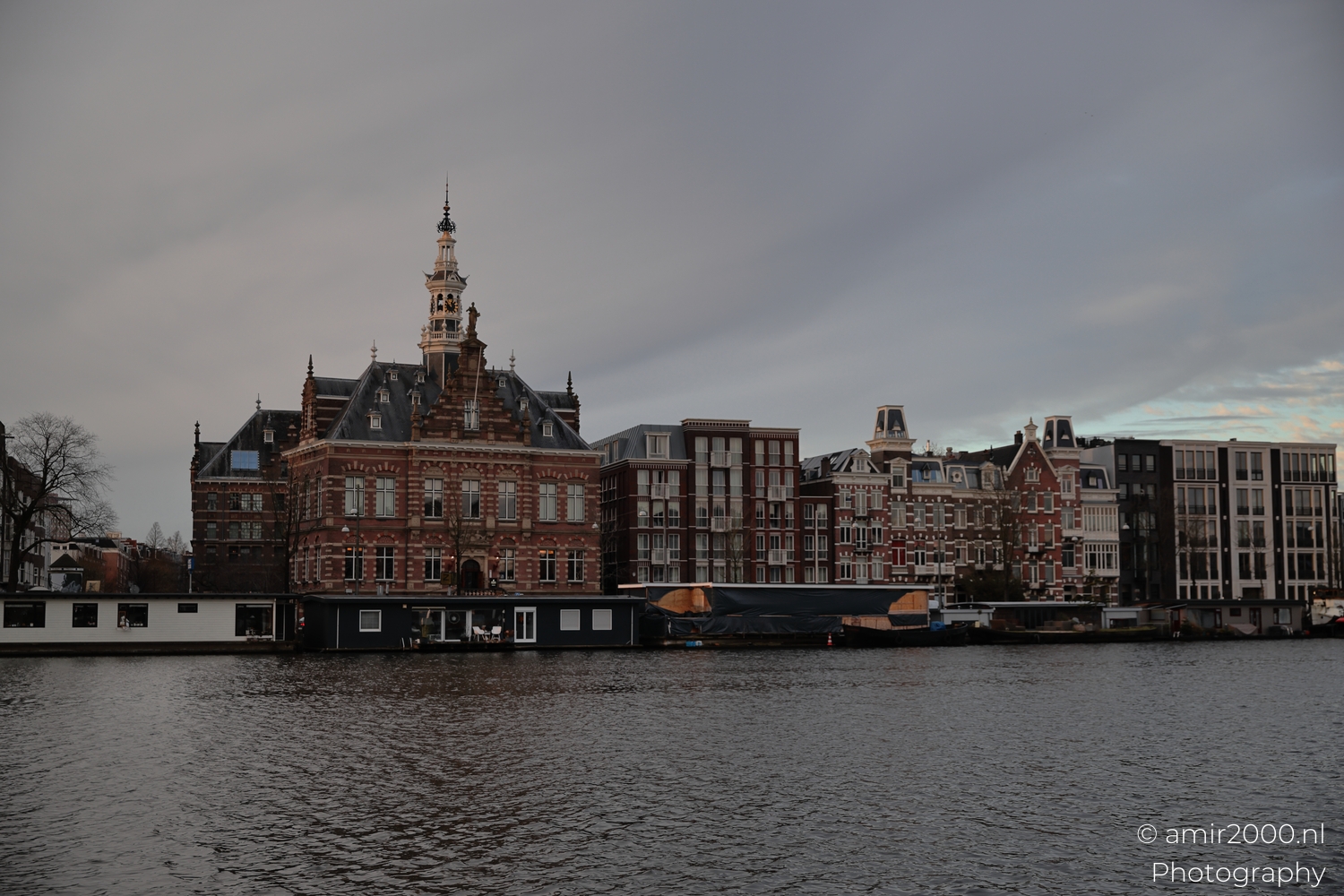 Front facing view of former town hall across the Amstel in soft evening light