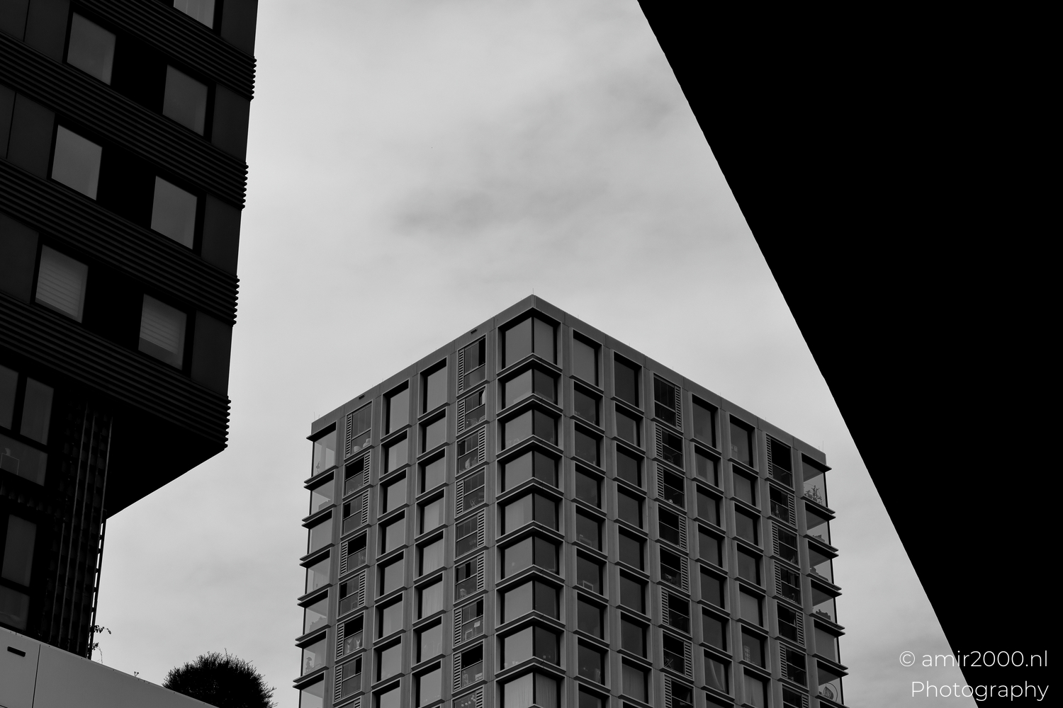 High-rise corner framed by dark foreground blocks at Amsterdam Sloterdijk, minimal sky and soft light.