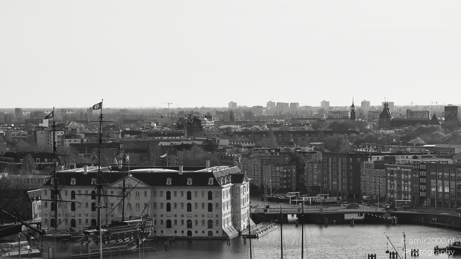 The Black and White National Maritime Museum with surrounding urban landscape featuring historical ships docked at a harbor.