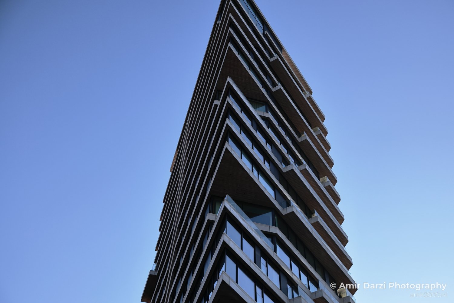 Facade view of architectural structure with strong geometric edges and shadows in Amsterdam Netherlands.