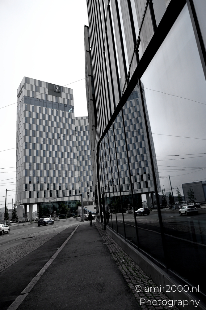 Street view toward Clarion Hotel Helsinki with reflective wall tram wires and soft overcast light near waterfront.