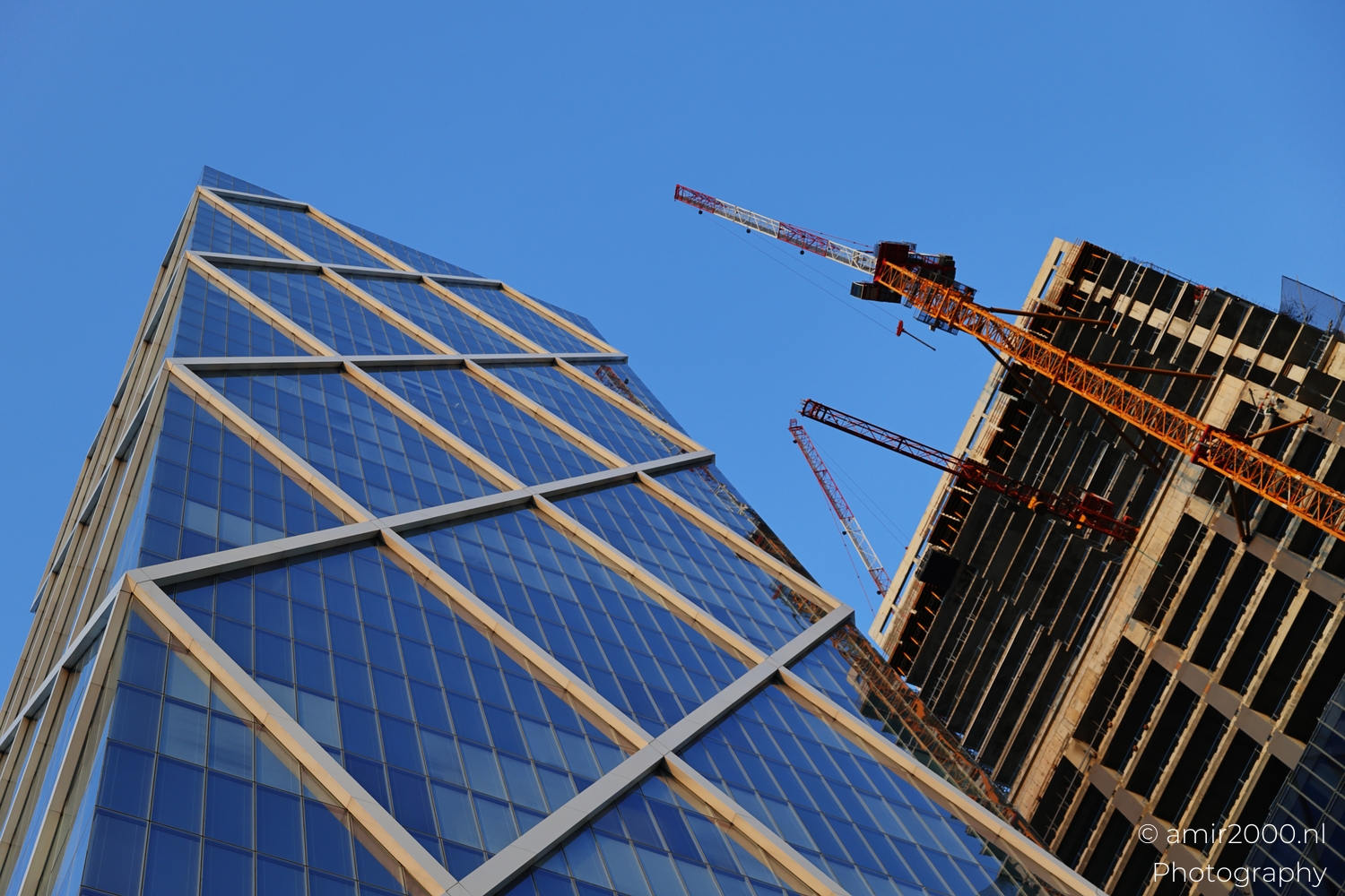 Glass tower with diagonal frame and orange crane arm, tilted low angle, dusk sky.