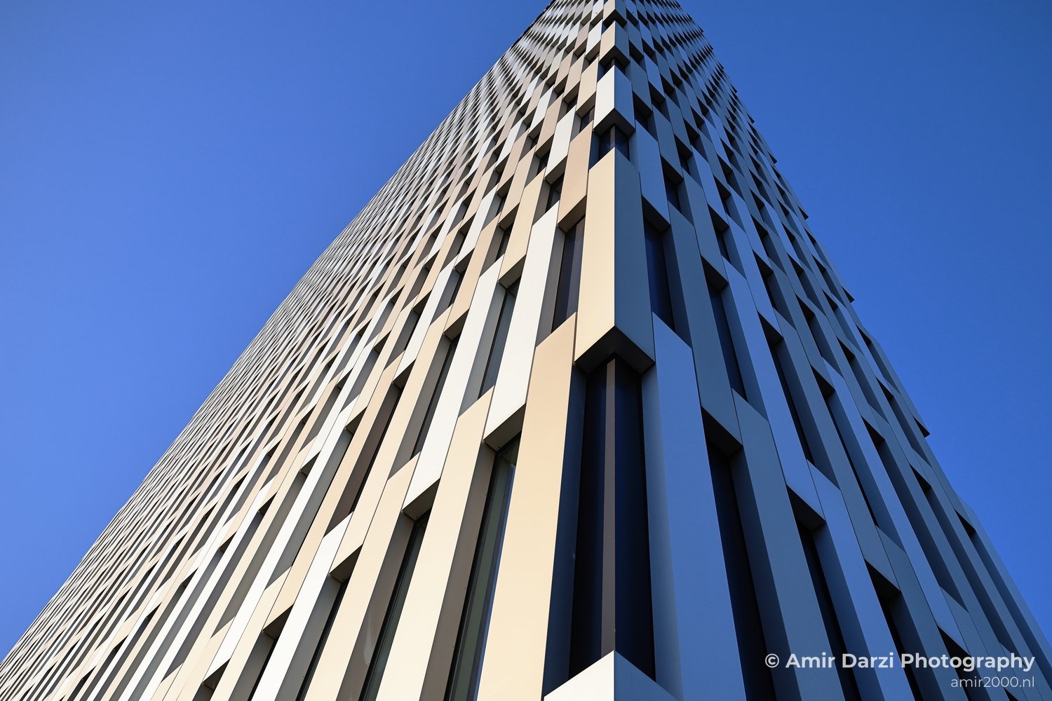 A modern skyscraper with reflective windows dominates an urban skyline view from Amsterdam Netherlands.