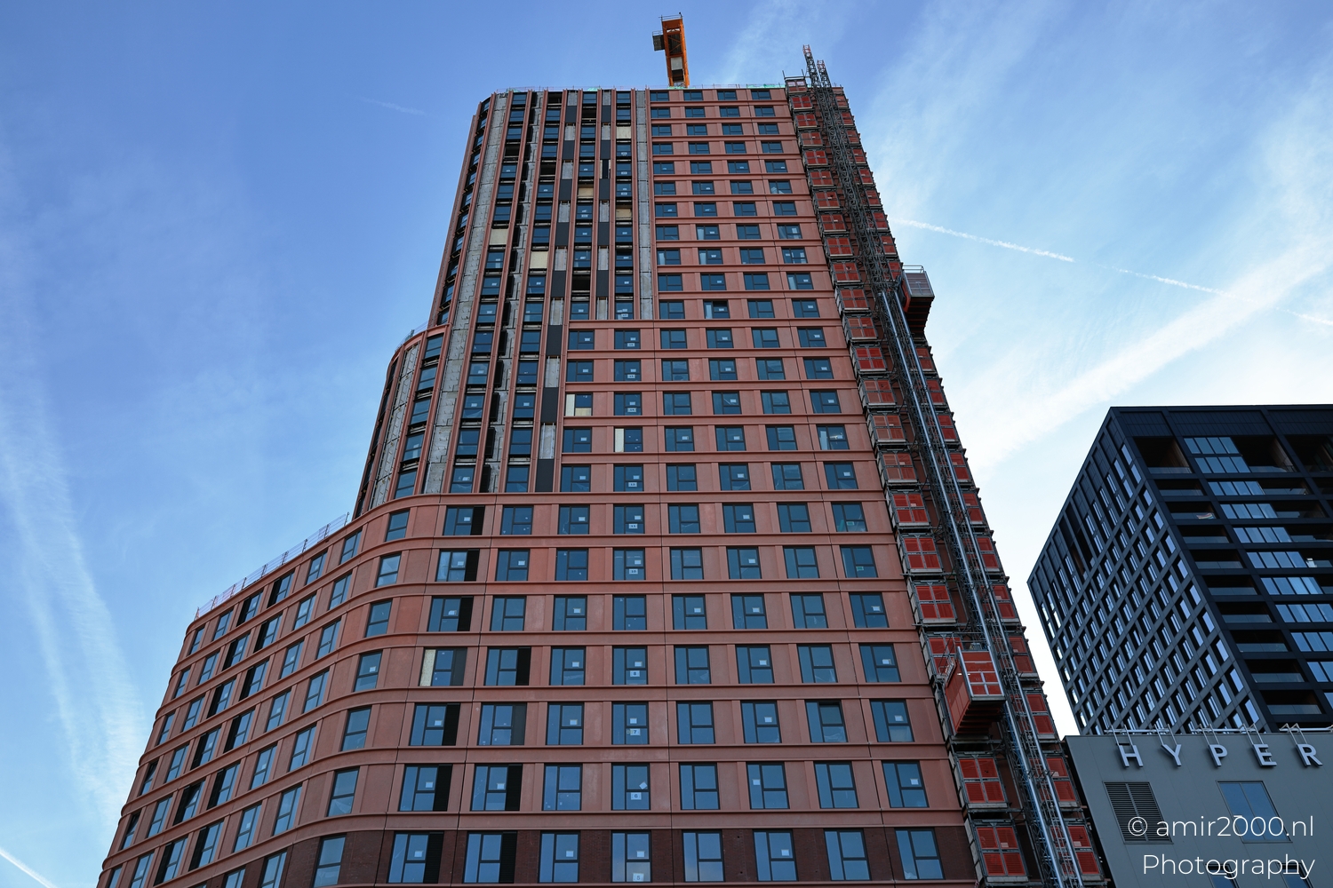 Rounded tower corner with vertical lines and construction lift in winter light