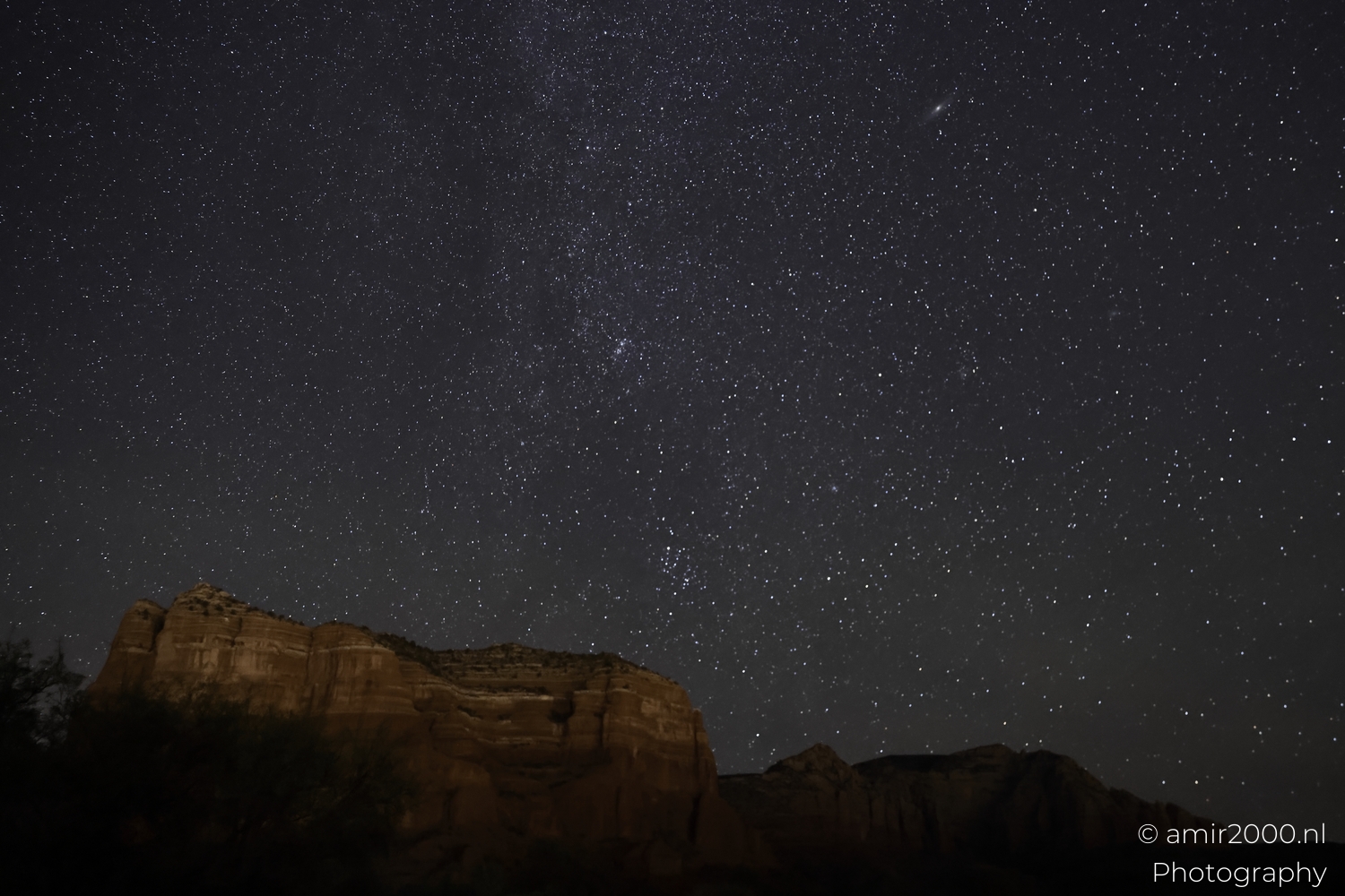 Bell Rock shape under dense starfield, soft haze and gentle glow, balanced wide night composition
