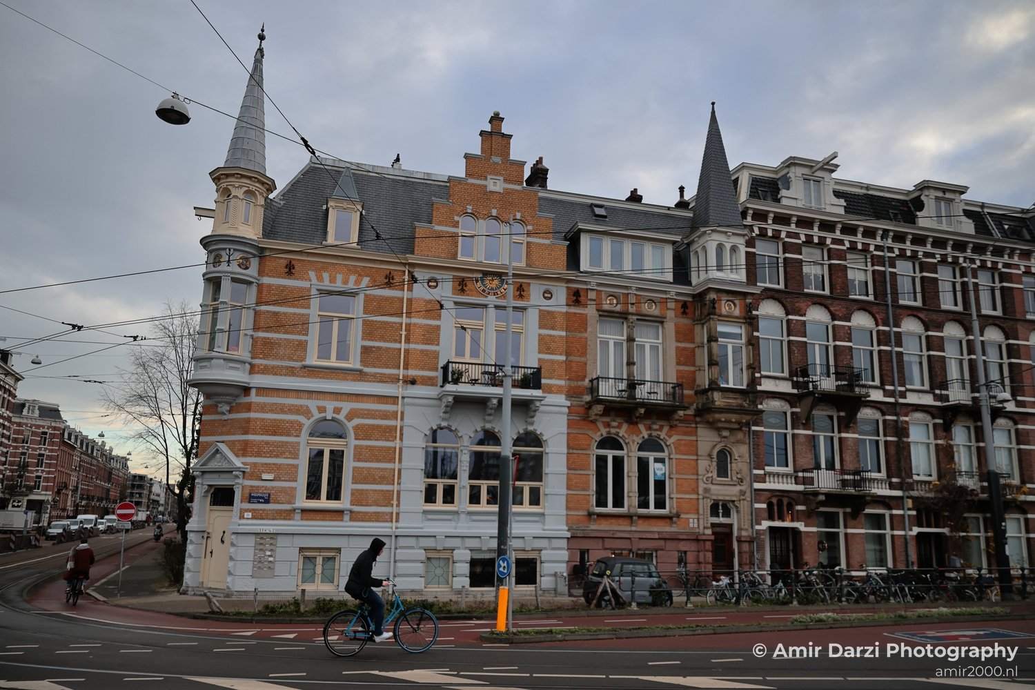 Cyclist on a street with historic buildings near canal-side streets in Amsterdam Netherlands.