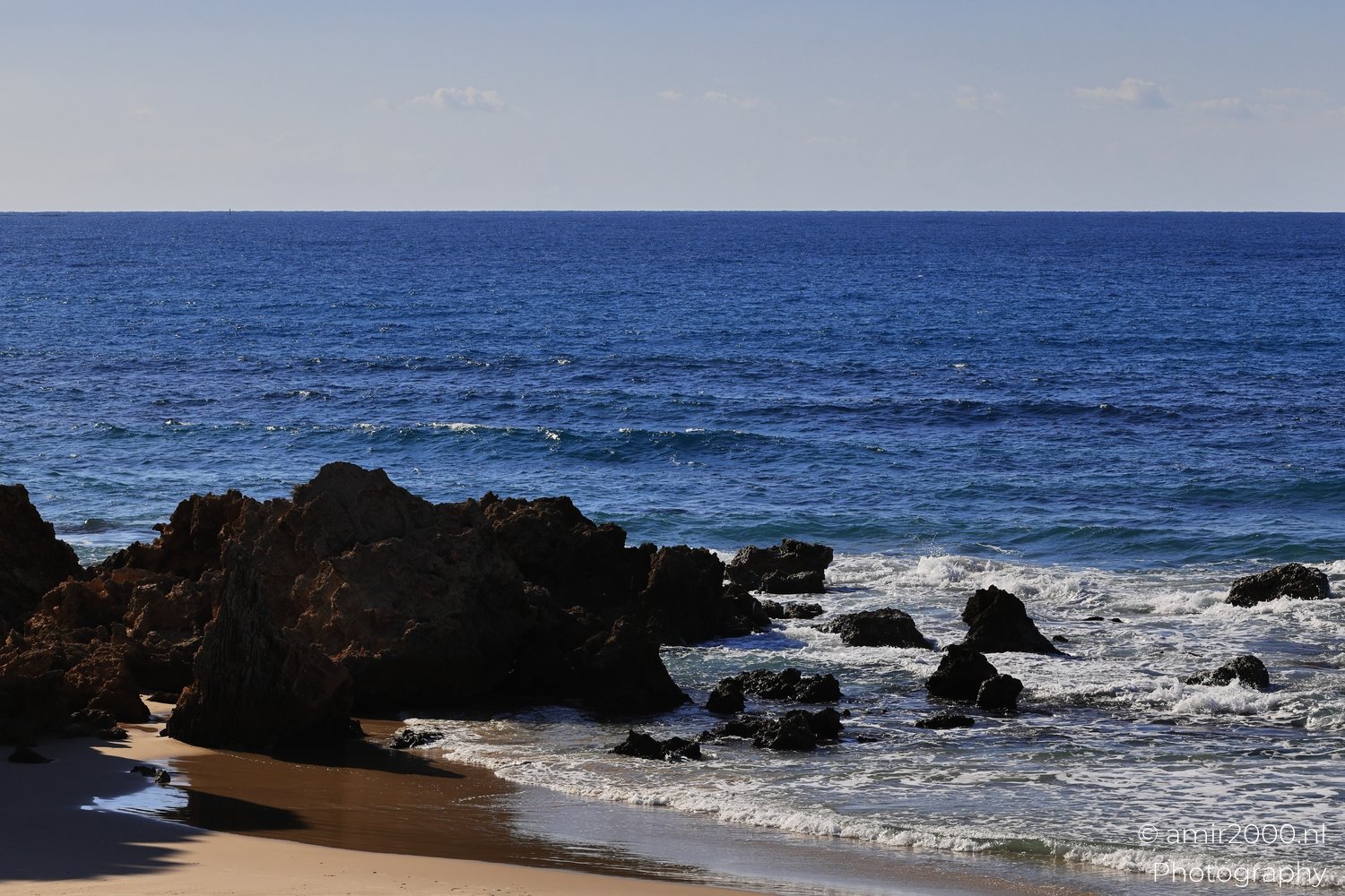 Dark cliffs and waves crashing on a beach in the Mediterranean Sea near Israel.