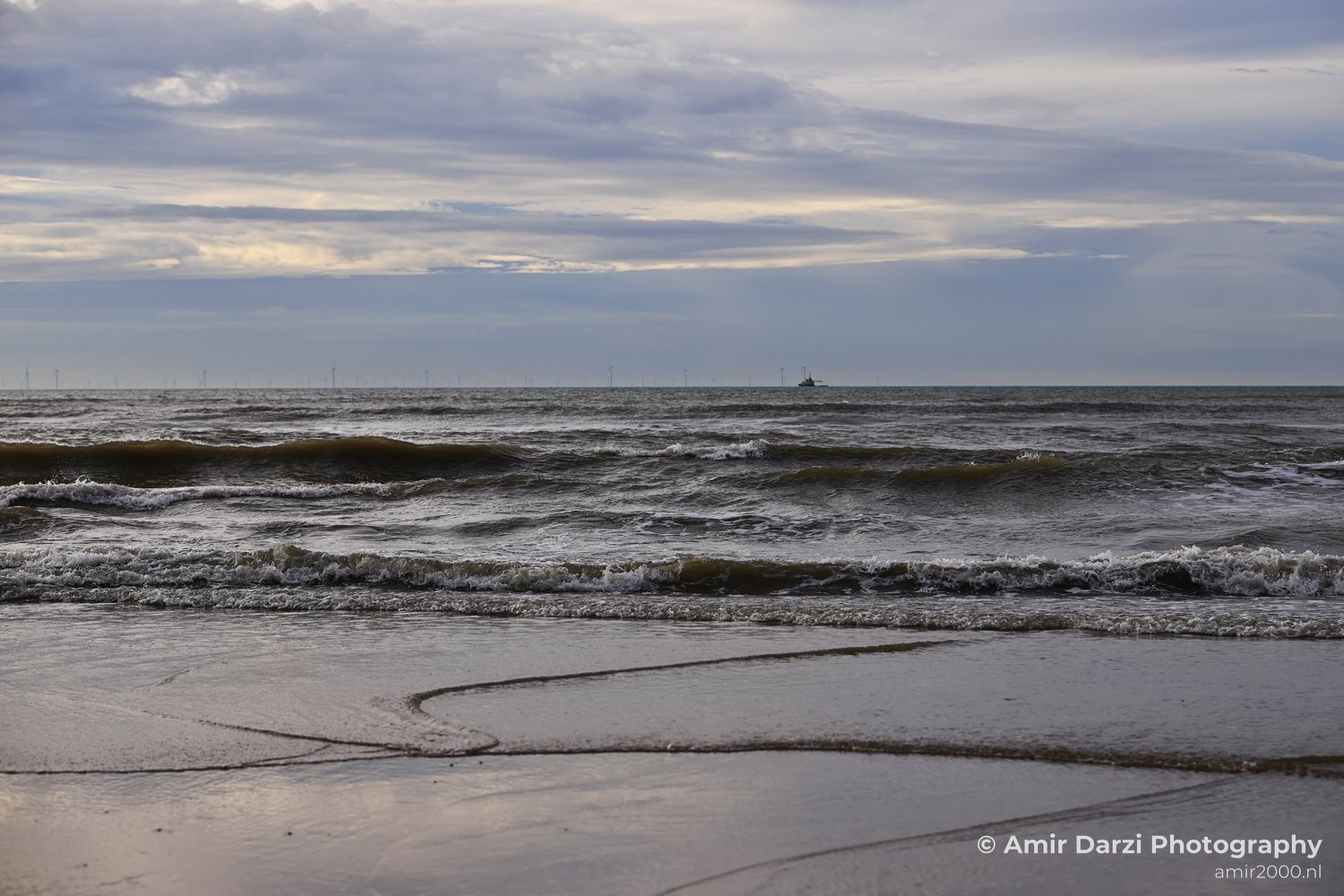Waves crashing on a beach near the Dutch coast during dusk hours.
