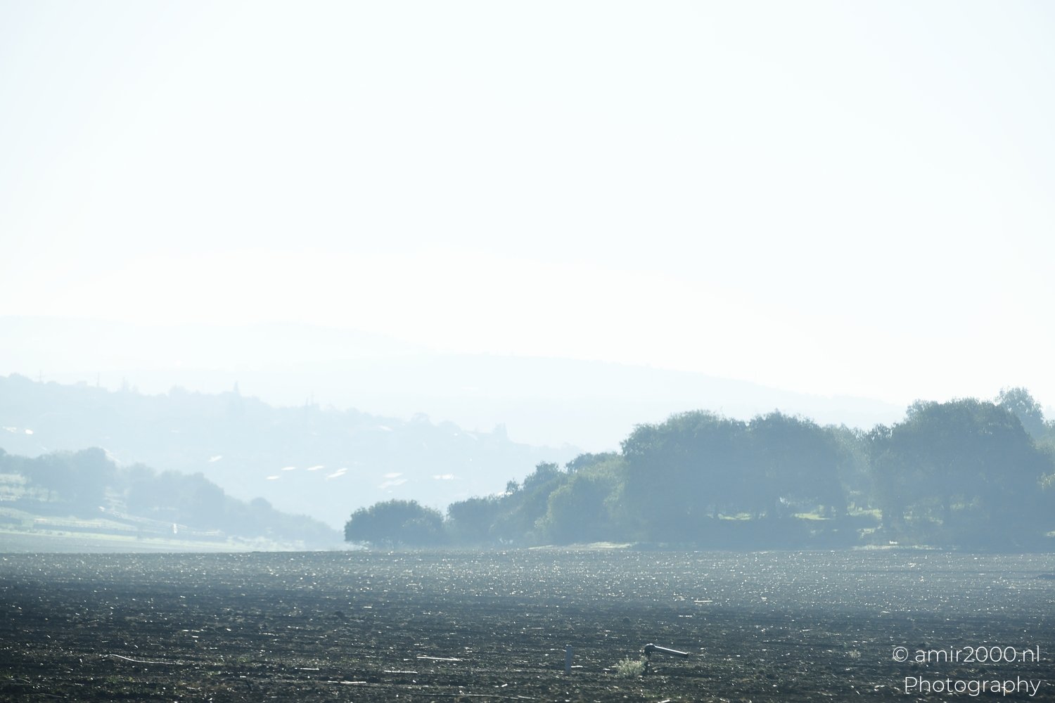 Distant hilltops obscured by haze above an agricultural field near Galilee Ha Galil Israel.