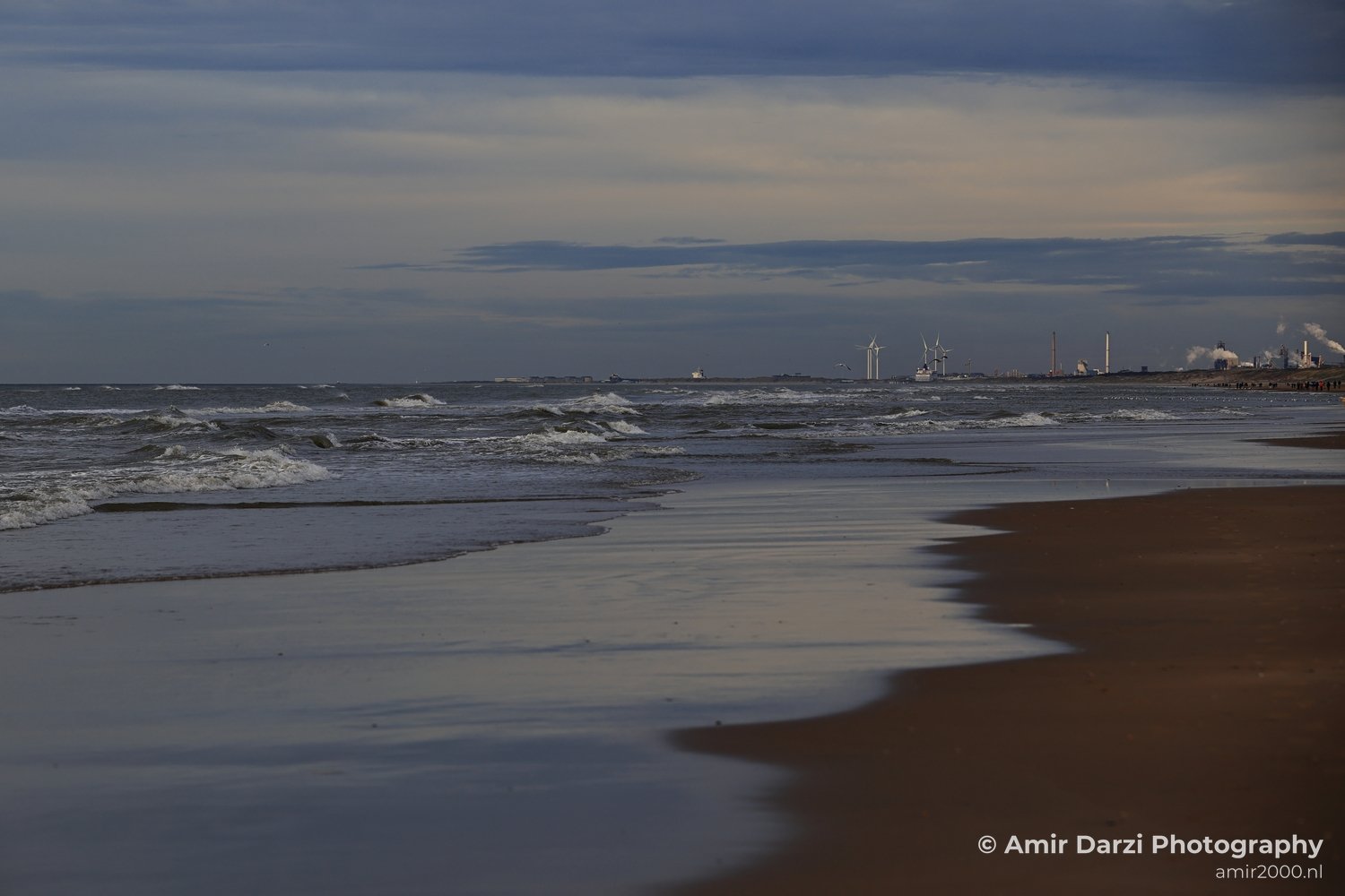 Wind turbines and gentle water near sandy shore in Zandvoort, Netherlands.