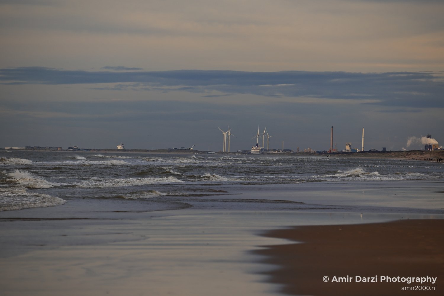 A coastal scene featuring windmills and gentle water waves at Zandvoort Beach.