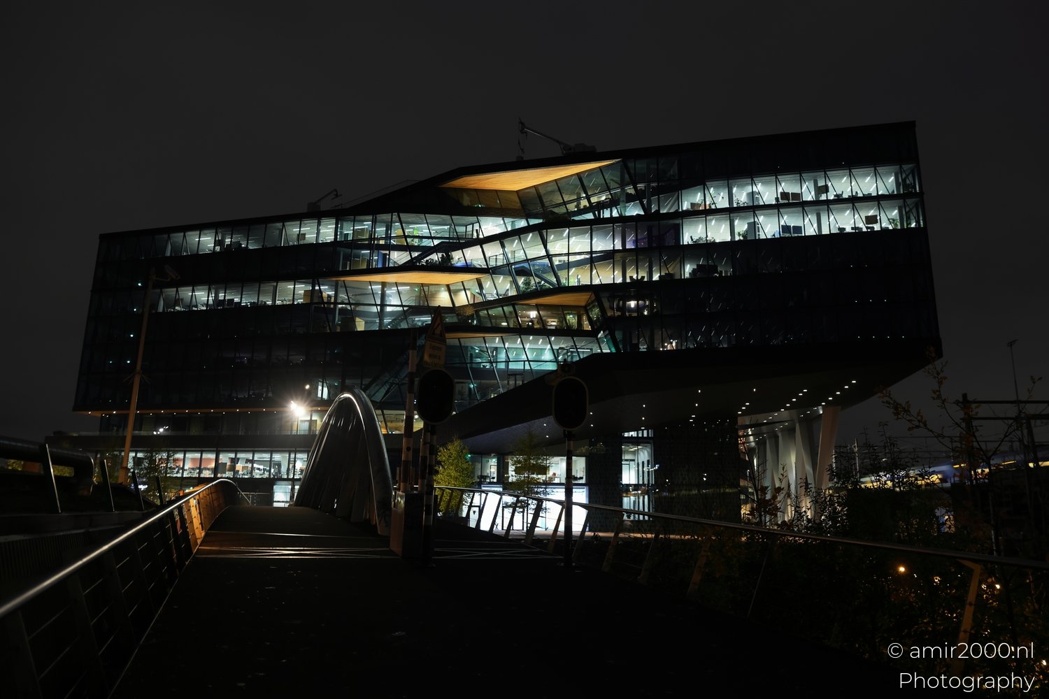 Glass-fronted structure lit from within in an urban setting during nighttime.