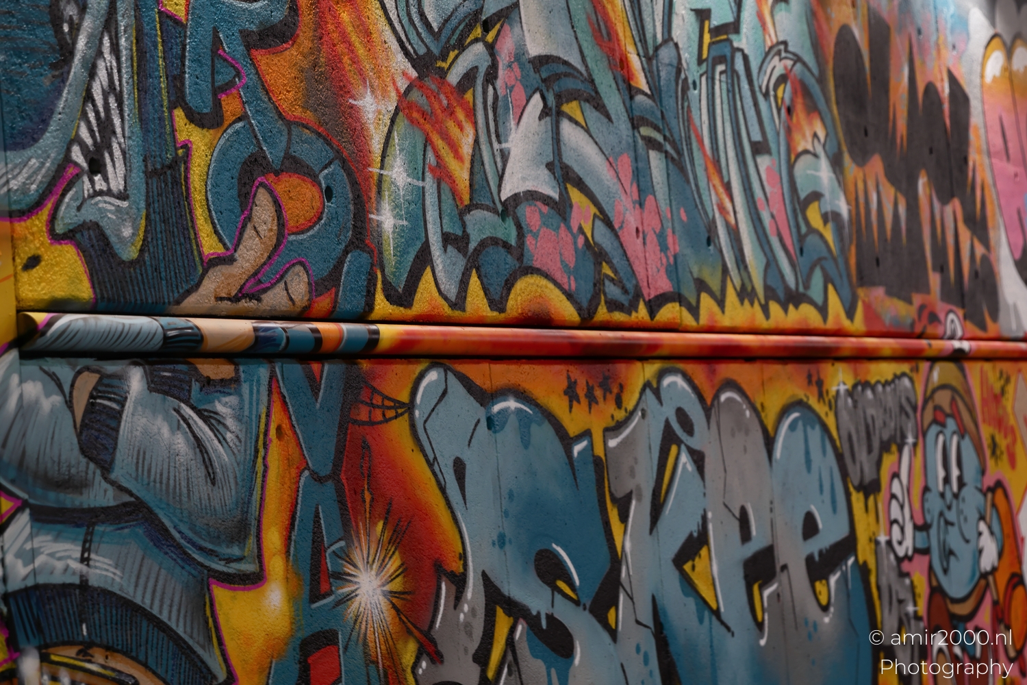 Row of parked bicycles in front of intricate graffiti wall with elephant head and layered lettering at night