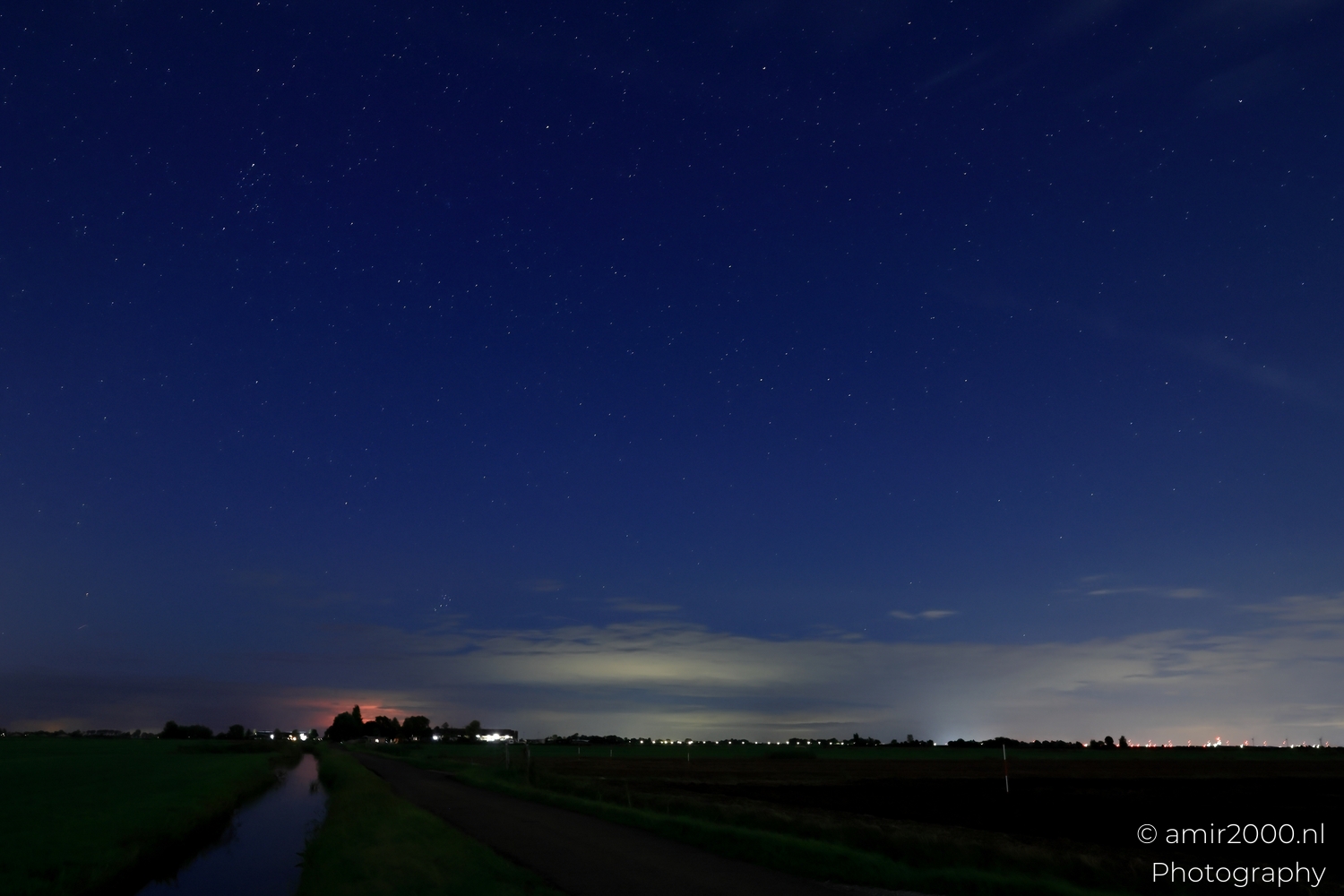 Deep blue star field with thin diagonal cloud bands and a gentle horizon gradient below.