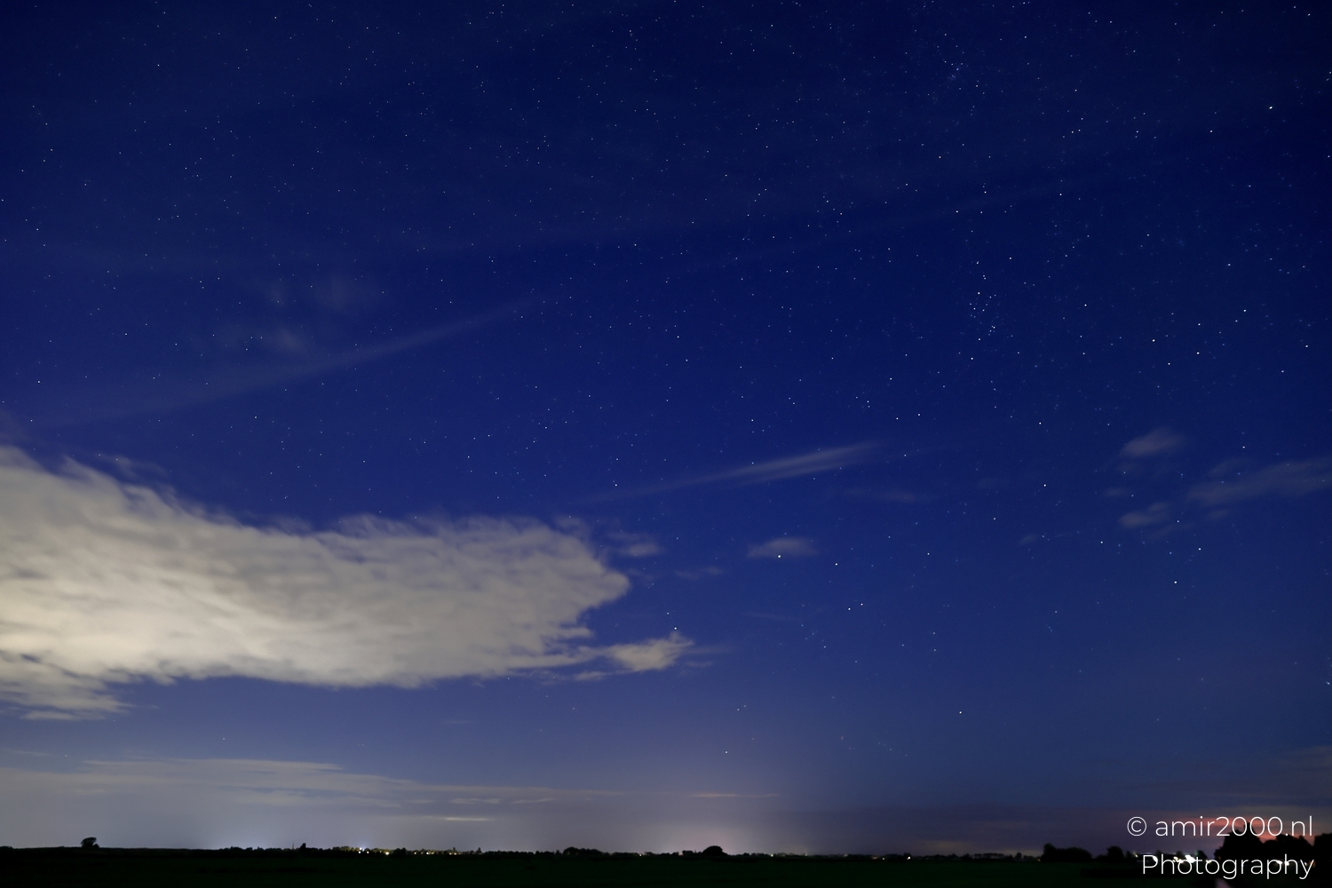 Feathered cloud plumes rising between point stars under gentle moonlight above flat Dutch fields.