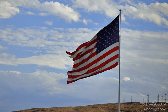 The American flag waves against the backdrop of scattered clouds and a dry landscape in Utah. - image from year 2025 #001
