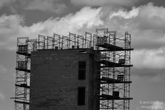 A building under construction with metal scaffolding against a cloudy sky. - image from year 2025 #007