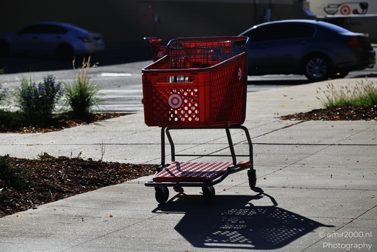 Empty Red Shopping Cart on Sidewalk Red plastic grocery cart sitting idle on city street in Denver image from year 2025 #1