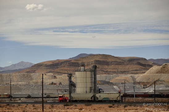 A large industrial facility with mountains in the background and a clear sky above. - image from year 2025 #001