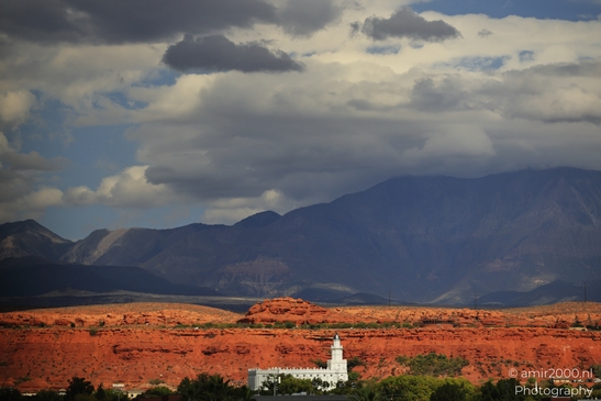 A white temple stands in front of a backdrop of red rock formations and distant mountains under - image from year 2025 #003
