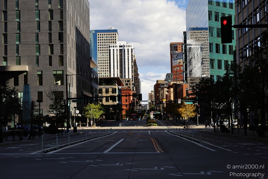 A wide city street leading towards a downtown skyline with modern buildings under partly cloudy - image from year 2025 #028