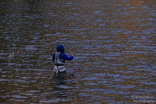 A person in a blue jacket and gray waders fishes waist-deep in Dillon Reservoir. - image from year 2025 #002
