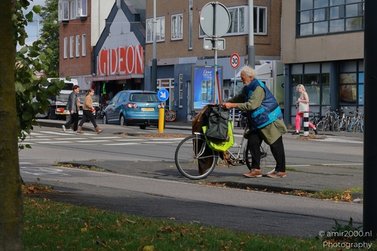 In Amsterdam, a bicycle-friendly city, an elderly man with his bicycle at a crosswalk in - image from year 2025 #001
