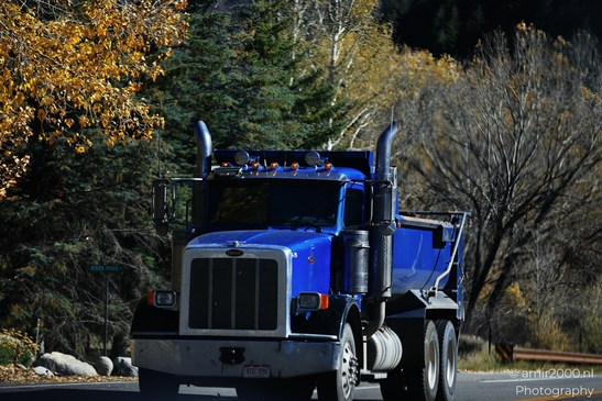 Blue dump truck transporting cargo through an outdoor rural area during autumn season. image from year 2025 #1
