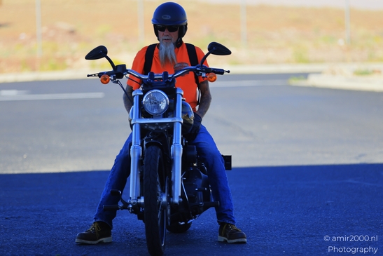 Motorcycle Ride Through Desert in Transportation Collection. A bearded man in an orange vest - image from year 2025 #004