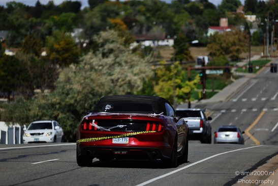 A red convertible Mustang car with caution tape on its rear is driving down a highway. - image from year 2025 #001