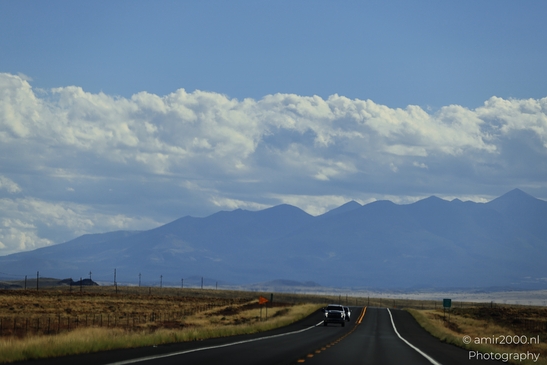 On The Way In Western USA in Transportation Collection. A lone car on a desert highway under a - image from year 2025 #037