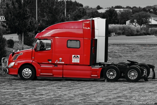 A red semi-truck with a white trailer parked on an unpaved surface. - image from year 2025 #002