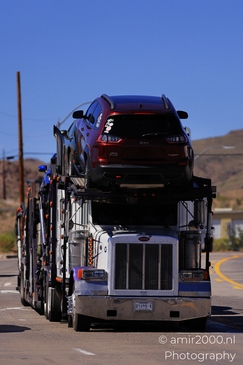 Trucks In Western USA in Transportation Collection. A red SUV being transported on a flatbed - image from year 2025 #013