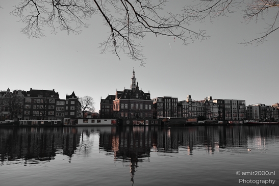 A serene riverside scene with historic buildings reflected on calm water in Amsterdam - image from year 2025 #006