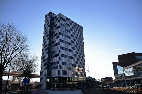 A glass facade skyscraper in Amsterdam Netherlands with a clear blue sky as its backdrop. - image from year 2025 #003