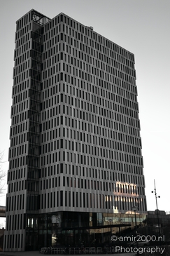A modern high-rise building with a dark exterior and reflective windows in Amsterdam Netherlands. - image from year 2025 #004