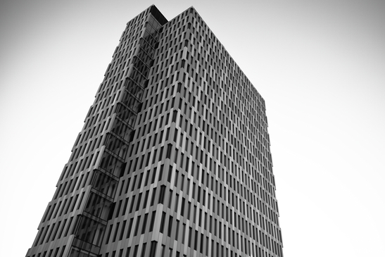 A tall skyscraper with a geometric facade stands in black and white - image from year 2025 #006