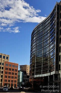 A contemporary office building with a curved design reflects its surroundings on a sunny day in - image from year 2025 #005