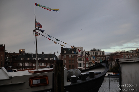 Boat_With_Colorful_Flags_On_A_Cloudy_Day_In_Amstel_Canal_Amsterdam_Netherlands_Cityscape_Photography_Canon_EOS_R5_Mark_II_2025_001.JPG