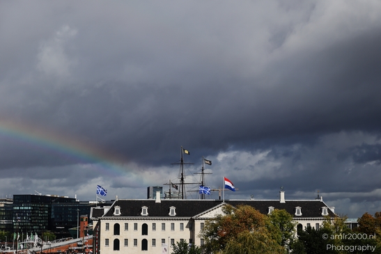 Rainbow arcs over Amsterdam's historic buildings under a tempestuous sky in Amsterdam - image from year 2025 #001