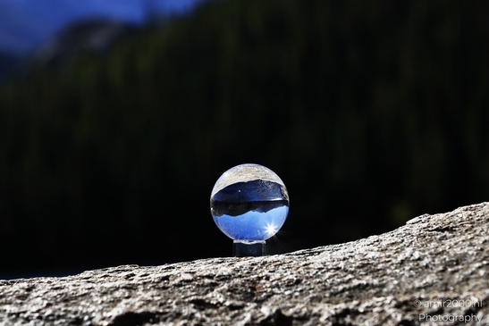 A glass ball sits on a rock in the Rocky Mountain National Park, reflecting the surrounding - image from year 2025 #001