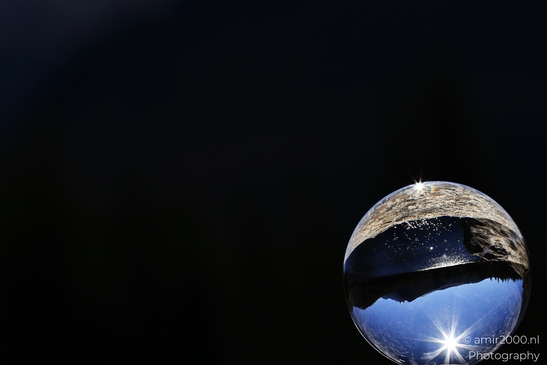 A glass ball reveals a reflected road and trees through Rocky Mountain National Park, Glass Ball - image from year 2025 #005