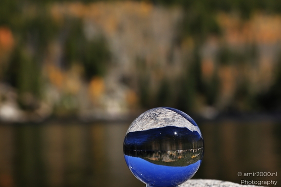 A glass ball reflects autumn colors and terrain while mirrored lake remains visible in Rocky - image from year 2025 #007